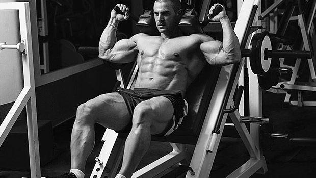 Muž trénujúci na leg press stroji v posilňovni, s viditeľne vypracovanými svalmi a dôrazom na posilňovanie nôh. Obrázok zobrazuje intenzitu a sústredenie pri silovom tréningu pre zlepšenie svalovej hmoty a kondície.